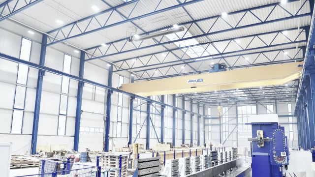 Ein Dunkelstrahler in einer großen Produktionshalle mit blauen Stahlträgern.